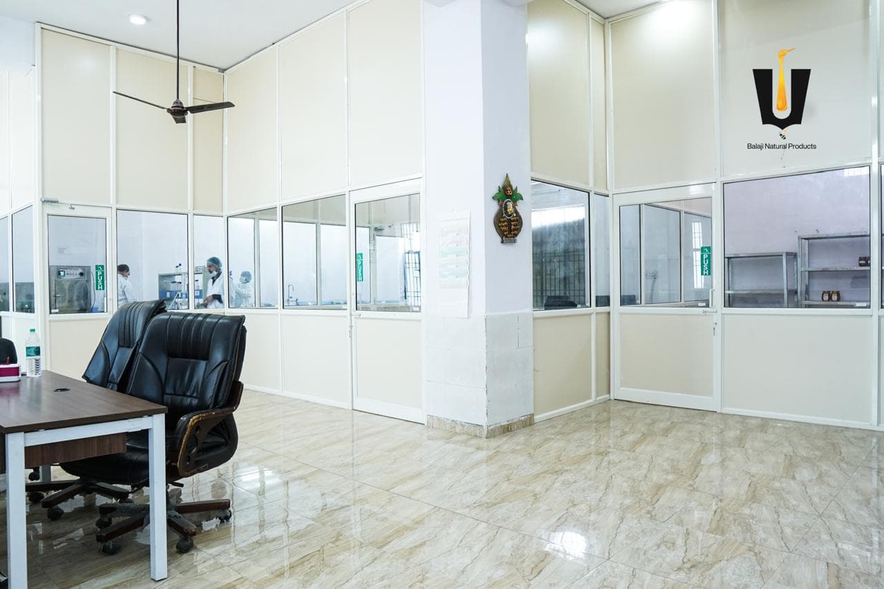 Glass-walled laboratory rooms and office desks inside the Balaji Natural Products facility